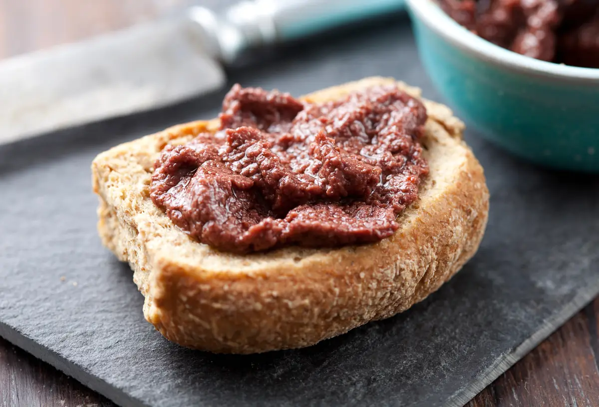 Pastă de măsline Kalamata întinsă pe pâine prăjită.